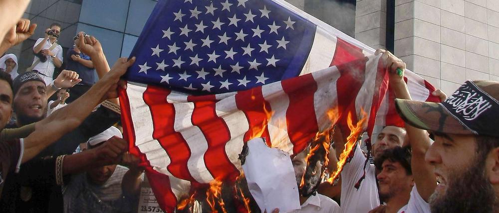 Tunesische Demonstranten verbrennen eine US-Flagge und hissen stattdessen eine islamistische.