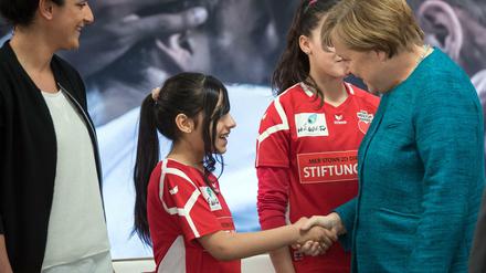 Willkommen war selten. Die Kanzlerin und eine junge Spielerin der Stiftung des 1. FC Köln "Wir zusammen"