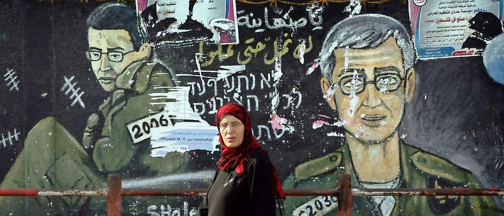 Eine Palästinenserin läuft im Gazastreifen an einem Wandbild des gefangenen israelischen Soldaten Gilad Schalit vorbei.