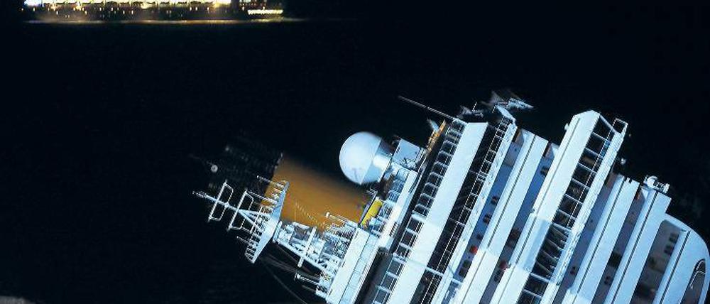 Unbeirrt. Während die Costa Concordia auf dem Felsen liegt, fährt ihr Schwesterschiff Costa Serena hell erleuchtet vorbei. Das Schiff fährt dieselbe Route wie die Costa Concordia und bietet das gleiche Programm.