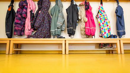 Jacken von Kindern hängen an der Garderobe einer Kita.