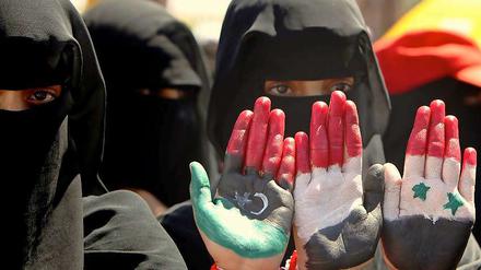 Regierungskritische Demonstranten im Jemen zeigen ihre Handflächen, die mit der libyschen, der jementischen und der syrischen Flagge bemalt sind. Der Wandel in Libyen, Ägypten und Tunesien weckt die Hoffnung der Bevölkerung.