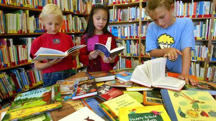 Schüler einer vierten Klasse lesen in einer Grundschul-Bibliothek.