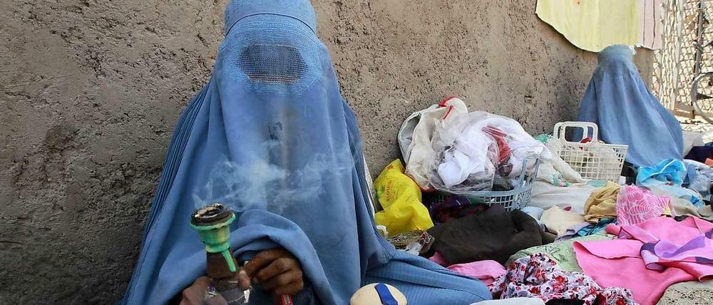 Auch nach zwölf Jahren Nato-Einsatz ist in Afghanistan vieles beim Alten: Eine Frau in Burka verkauft am Straßenrand in Herat alte Kleider.
