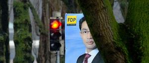 Das Bild zeigt ein Wahlplakat von FDP-Chef Philipp Rösler vor einer roten Ampel.