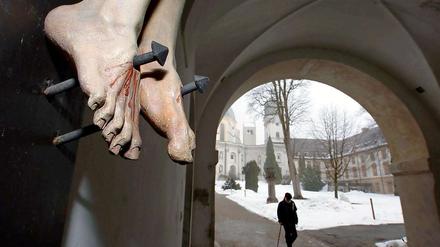 Die Füße einer gekreuzigten Christusfigur, aufgenommen am im Eingangsbereich des Klosters Ettal. Kinder wurden geschlagen und sexuell missbraucht. Die Vorfälle wurden vertuscht, Täter geschützt, Opfer alleingelassen. 