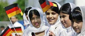 Muslimische Mädchen schwenken deutsche Fahnen.