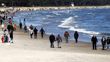 Urlauber spazieren über den Ostseestrand in Binz.