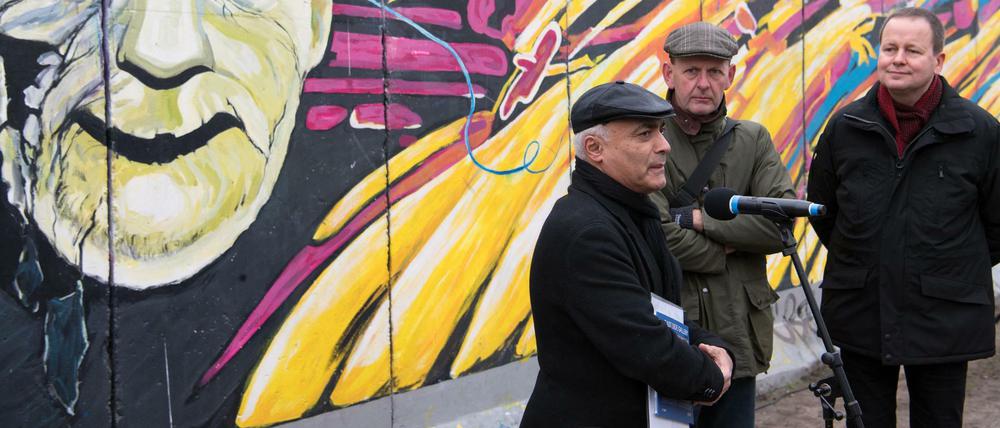 Kani Alavi (l.), Gründer der Künstlerinitiative East Side Gallery e.V., Axel Klausmeier (M.), Direktor der Stiftung Berliner Mauer, und Klaus Lederer (Die Linke), Berlins Kultursenator, vor der East Side Gallery.