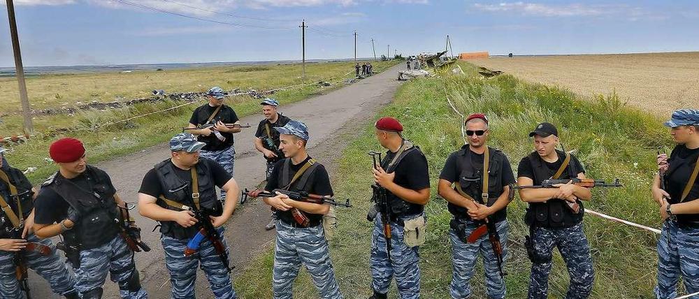 Bewaffnete Separatisten bewachen Wrackteile des abgestürzten Flugzeugs. 
