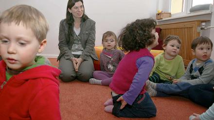 Senatorin Sandra Scheeres schaut zu, wie ein Erzieherin mit Kindern eines INA-Kindergartens singt.