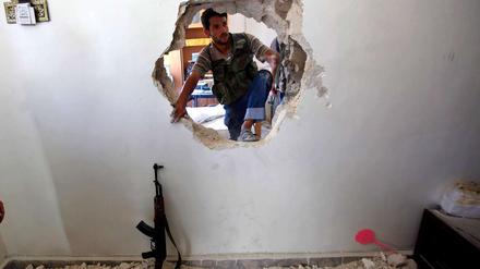 Ein Durchbruch? Der syrische Vizepremier hat den Rücktritt Assads als verhandelbar bezeichnet. Dieser Rebellenkämpfer bricht zunächst nur in den nächsten Raum durch - auf der Suche nach Überlebenden in einem in Teilen zerstörten Haus.