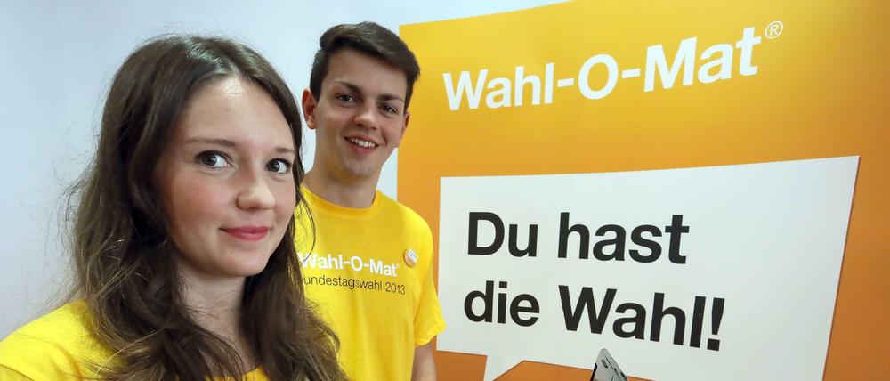 Zwei Jugendredakteure der Bundeszentrale für Politische Bildung stehen beim Start des interaktiven Online-Tools Wahl-O-Mat 2013 vor dem Logo.