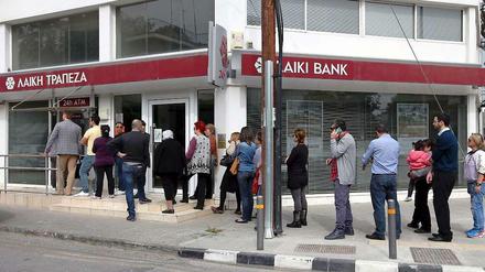 Menschen stehen Schlange, um Cash aus dem Geldautomat einer geschlossenen Bank in Nikosia zu bekommen.