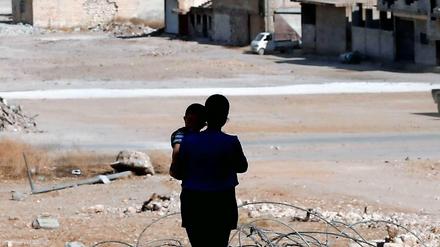 Eine syrische Frau mit ihrem Kind vor den Trümmern von Kobane.