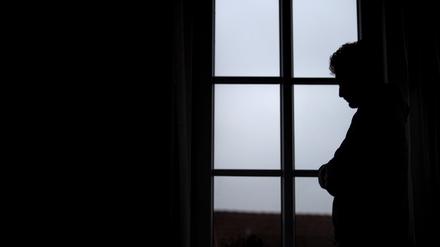 Ein Mann steht am Fenster seiner Wohnung. (Symbolbild, gestellte Szene)