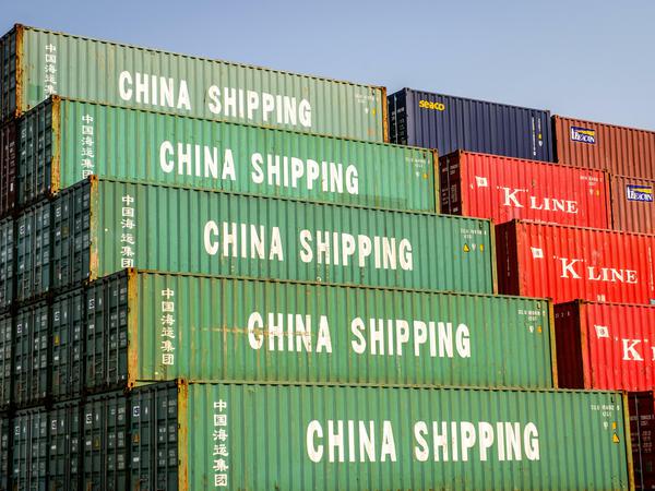 Container mit der Aufschrift "China Shipping" liegen aufgestapelt in einem Containerhafen. 