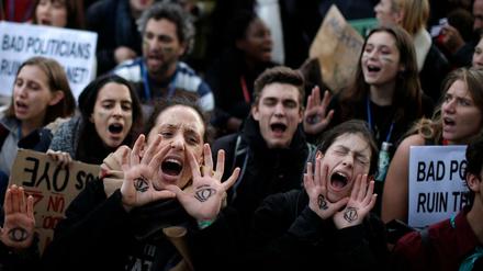 Klima-Aktivisten, die sich ein "wachsames" Auge auf die Handfläche gemalt haben, protestieren in Madrid.