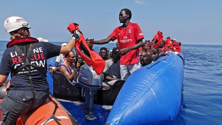 Eine Helferin des Rettungsschiffs "Eleonore" gibt Westen an Flüchtlinge auf einem Boot aus.