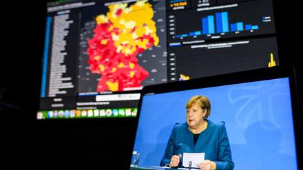 Kanzlerin Angela Merkel bei der Pressekonferenz zum Teil-Lockdown, im Hintergrund die deutsche Corona-Karte