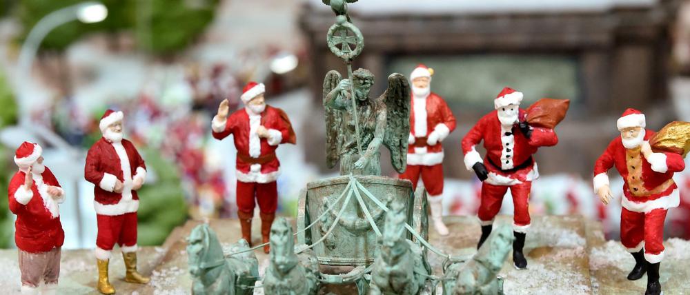 In Berlin eher folkloristisch als fromm: Miniatur-Weihnachtsmänner stehen neben einer Miniatur-Quadriga auf dem Miniatur-Brandenburger-Tor. 