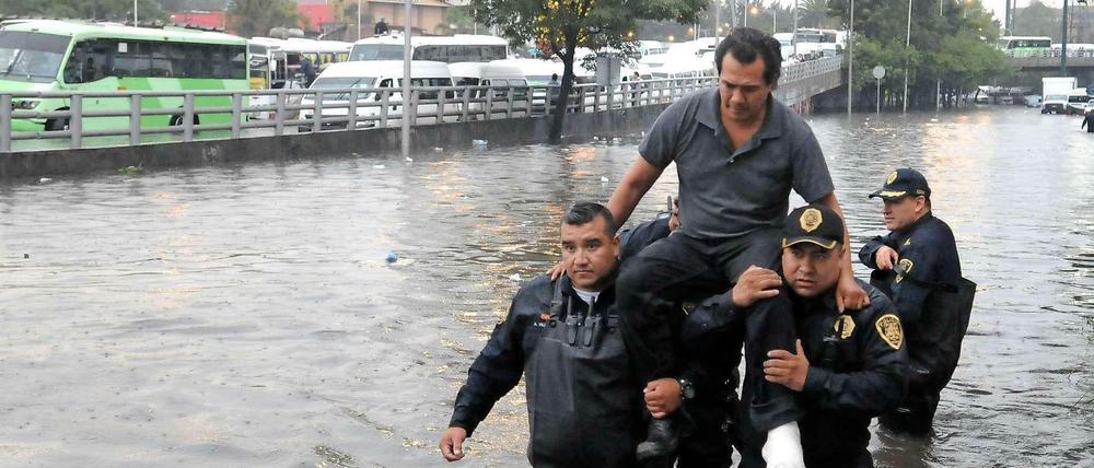 Polizisten tragen einen Mann nach einem Unwetter durch eine überschwemmte Straße in Mexiko-Stadt. Für Mega-Städte ist es besonders schwer, sich an den Klimawandel anzupassen. 