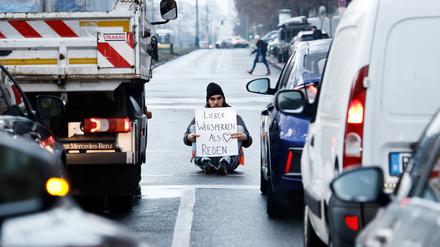 Ein Aktivist zeigt ein Schild mit der Aufschrift „Lieber Wegsperren als Reden“ bei einer Sitzblockade mit weiteren Aktivisten auf der Prenzlauer Allee. (Symbolbild)
