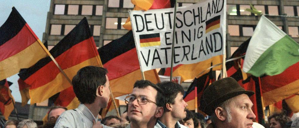 DDR-Bürger während einer Demonstration in Dresden am 19.12.1989 mit Deutschland-Flaggen.