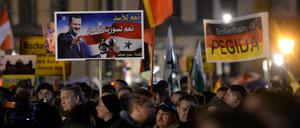 Pegida-Demonstration am 9. November in Dresden: Anhänger halten ein Plakat mit dem Antlitz des syrischen Präsidenten Baschar al-Assad hoch, auf dem in arabischer Schrift steht: "Wir sagen Ja zu Assad, Ja zu einem Syrien, das sicher ist".   