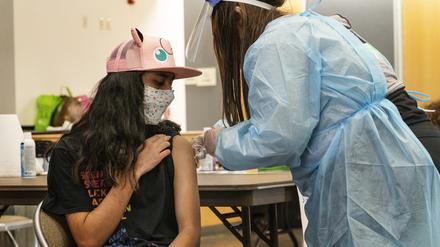 24.05.2021, USA, San Pedro: High-School-Neuling Jeff Eseroma, 14, wird in einer schulbasierten Corona-Impfklinik für Schüler ab 12 Jahren in San Pedro, Kalifornien, geimpft. Die Schulen setzen auf Maskottchen, Preise und Wettbewerbe, um Jugendliche ab 12 Jahren dazu zu bewegen, sich vor den Sommerferien gegen das Coronavirus impfen zu lassen. Foto: Damian Dovarganes/AP/dpa +++ dpa-Bildfunk +++