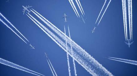 Flugzeuge mit Kondensstreifen. Das klimaschädliche am Fliegen sind nicht nur die Treibhausgasemissionen, sondern auch die Treibhauseffekte durch Kondensstreifen. 
