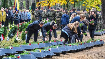 Schüler legen Blumen auf kleine Särge mit sterblichen Überresten von deutschen Soldaten auf dem Waldfriedhof in Halbe (Brandenburg) nieder. 