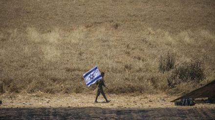 Ein israelischer Soldat hält eine israelische Flagge in einem Grenzgebiet.