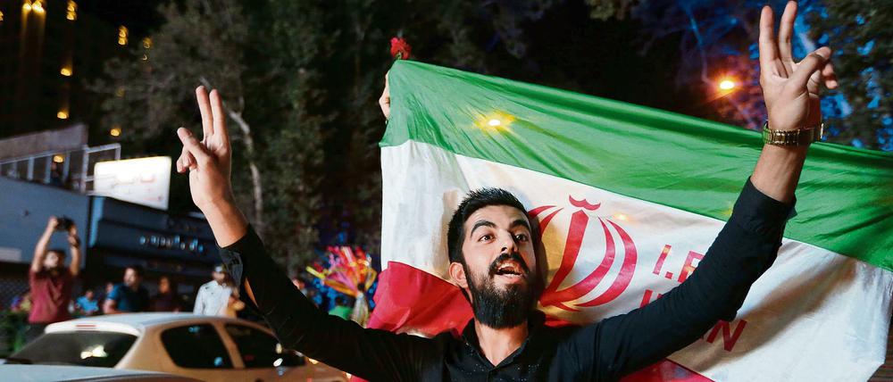 Im Iran wurde das Abkommen mit dem Westen über das Atomprogramm im Juli 2015 bejubelt. Ein Iraner zeigt in Teheran vor der Staatsflagge das Victory-Zeichen. 