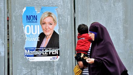 Passantinnen mit einem Jungen gehen im nordfranzösischen Valenciennes an einem Plakat der Front-National-Chefin Marine Le Pen vorbei.
