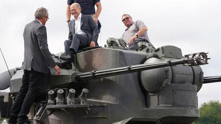 Bundeskanzler Olaf Scholz (Mitte) klettert auf einen Gepard Panzer.