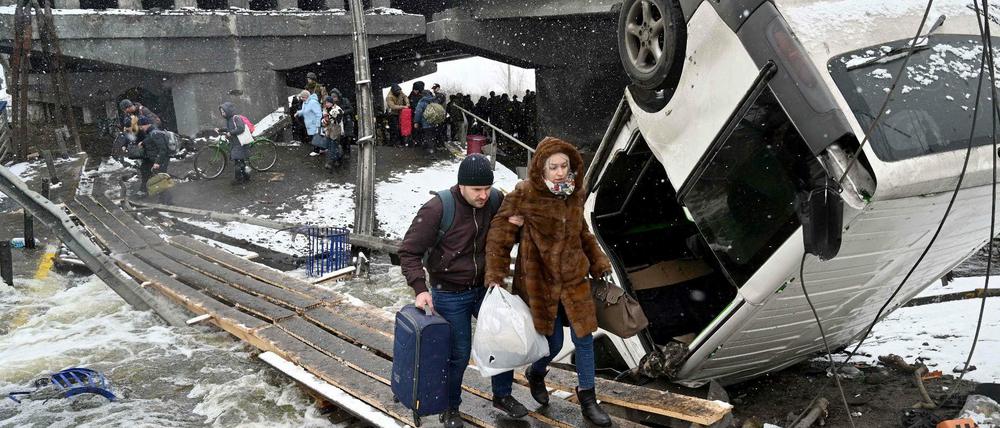 Ein Mann und eine Frau überqueren eine zerstörte Brücke in Irpin, nordwestlich von Kiew.