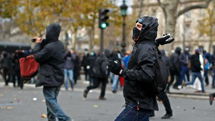 Ein Demonstrant attackiert die Polizei in Paris. 