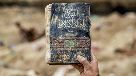 Ein Anti-IS-Kämpfer präsentiert ein Gesetzbuch aus der Zeit des „Kalifats“, das in Ostsyrien gefunden wurde.
