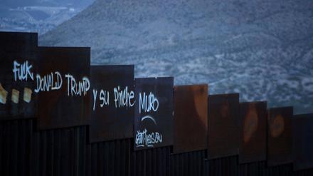 Ein Grenzzaun zwischen der USA und Mexiko mit einer Schmähung des US-Präsidenten