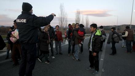 Ein griechischer Polizist stoppt afghanische Migranten auf dem Weg zur mazedonischen Grenze. 