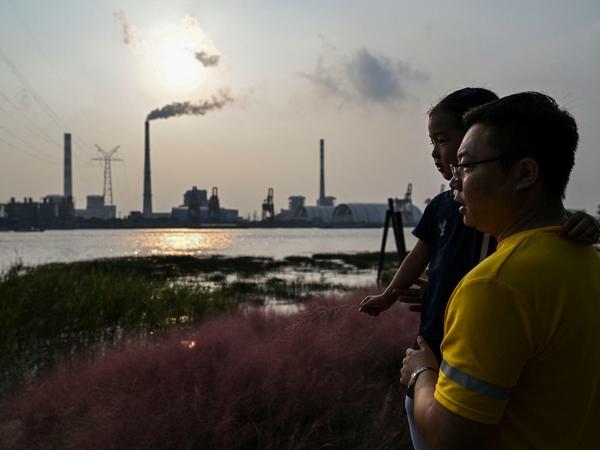 Ein Vater mit seinem Kind am Ufer des Huangpu gegenüber dem Wujing Kohlekraftwerk in Schanghai.