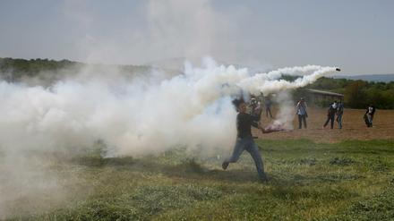 Flüchtlinge werfen Tränengasbomben zurück, die Polizisten am Grenzzaun zu Mazedonien abgefeuert haben.