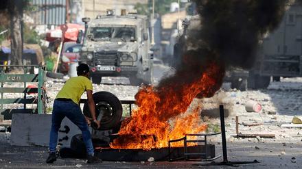 Ein palästinensischer Demonstrant wirft einen Reifen in ein Feuer.
