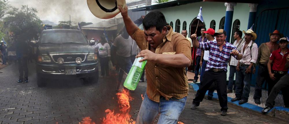 Ein Demonstrant in Nicaragua verbrennt bei den Protesten gegen den Bau des Nicaragua-Kanals eine Flagge der Sandinisten am Samstag in Juigalpa City. Die chinesische Betreibergesellschaft HKND will die 278 Kilometer lange Verbindung zwischen dem Pazifischen Ozean und der Karibik bis 2019 fertigstellen.