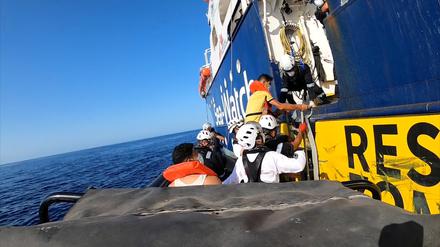 Migranten und Sea-Watch-Mitarbeiterinnen klettern an Bord. 