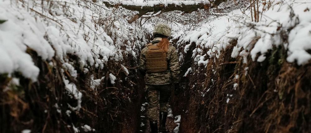 Eine ukrainische Soldatin läuft durch einen Graben nahe der russischen Grenze.