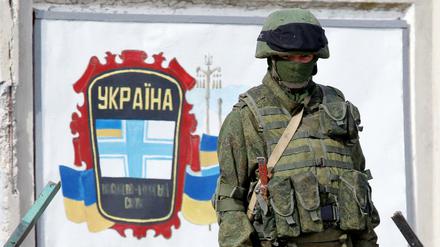 Ein Soldat in einer Uniform ohne Hoheitszeichen bewacht Anfang März 2014 eine ukrainische Militärbasis auf der Krim. 