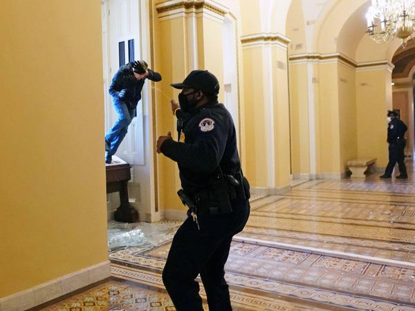Ein Polizist im Kapitol setzt Pfefferspray ein.