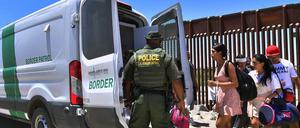 Ein US-Grenzschützer und lateinamerikanische Migranten an der mexikanischen Grenze mit Arizona.